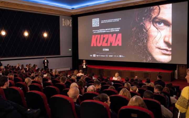 Full house at Kino Sõprus: the audience faces a big screen showing the poster of the film “Kuzma”, a host speaks on stage