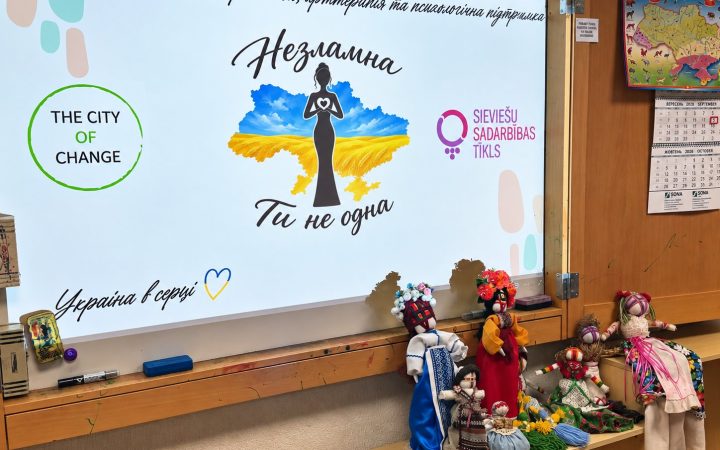 A screen reading “Nezlamna. You are not alone” and colourful motanka dolls made at the workshop